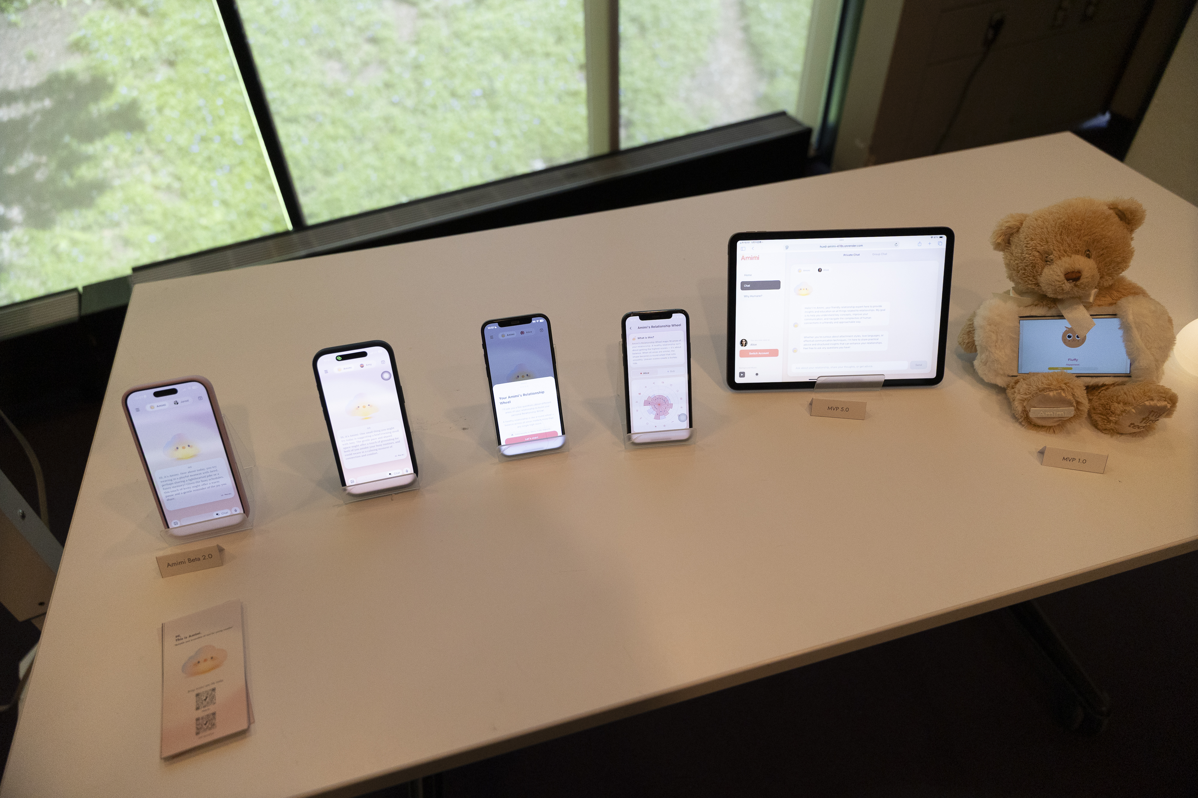 Amimi mobile screens, a tablet-based prototype, and the original teddy-bear prototype arranged on a table